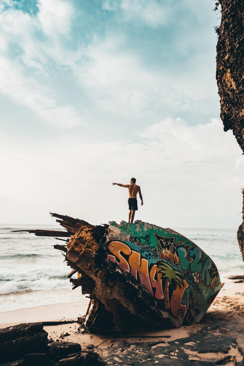 Free Image of Person standing on colorful graffiti boat wreck 