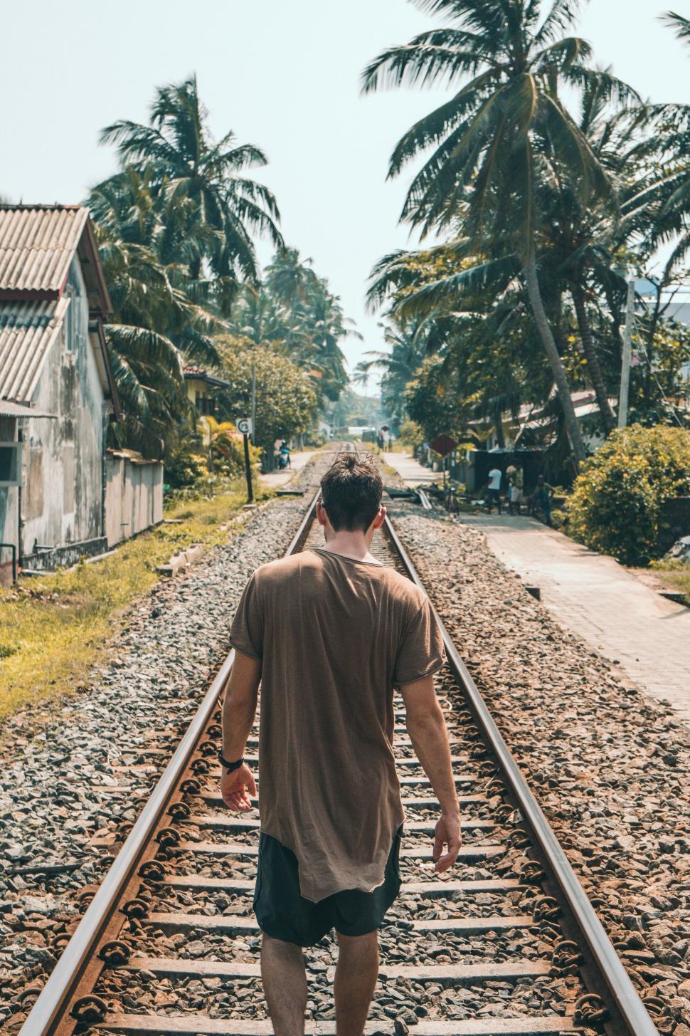 Free Image of Man walking along tropical railway tracks 