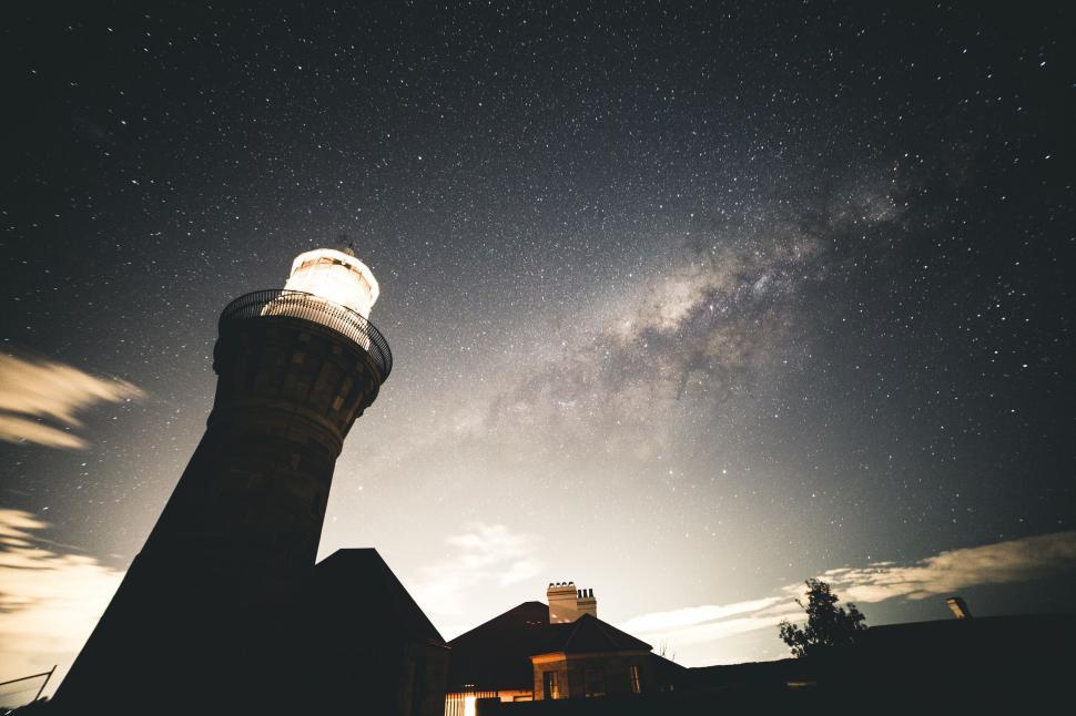 Free Image of Majestic lighthouse under a starry night sky 