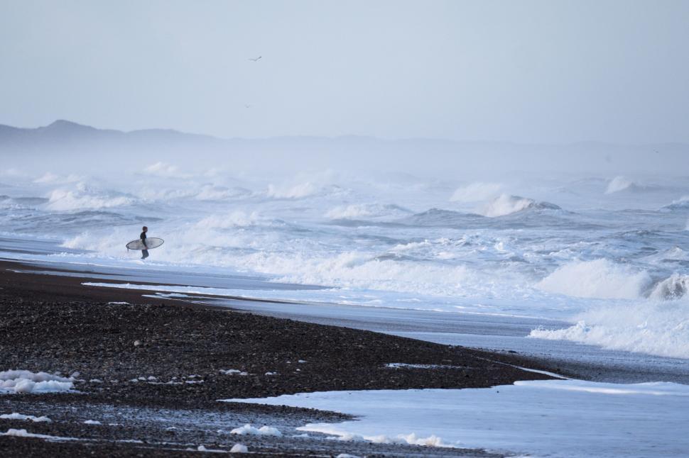 Free Image of Solitary surfer approaching tumultuous ocean waves 