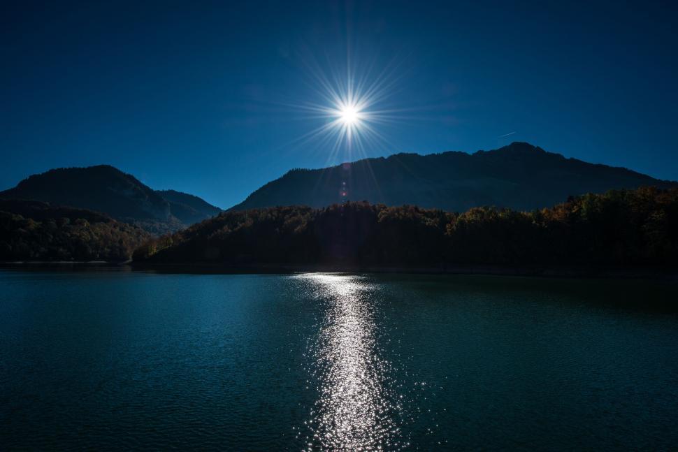 Free Image of Sunstar reflection over a tranquil lake 