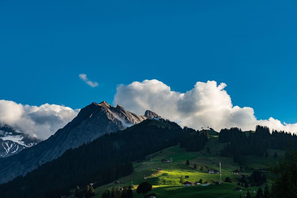 Free Image of Lush green hill under a dramatic cloud-filled sky 