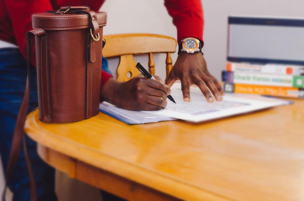 Free Image of Man writing at a desk with vintage bag 