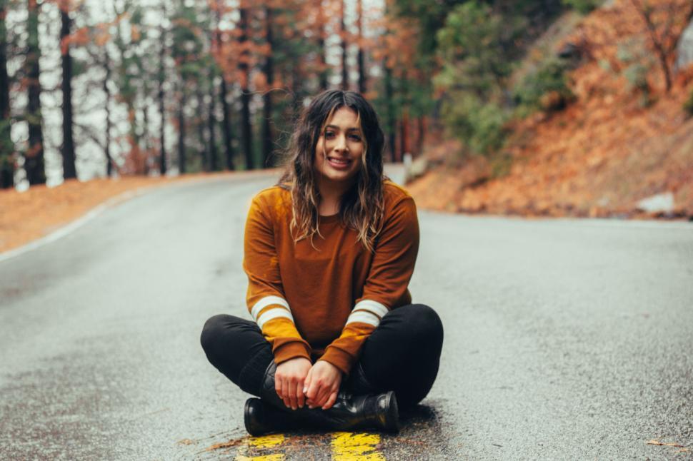 Free Image of Woman sitting on road with warm smile 