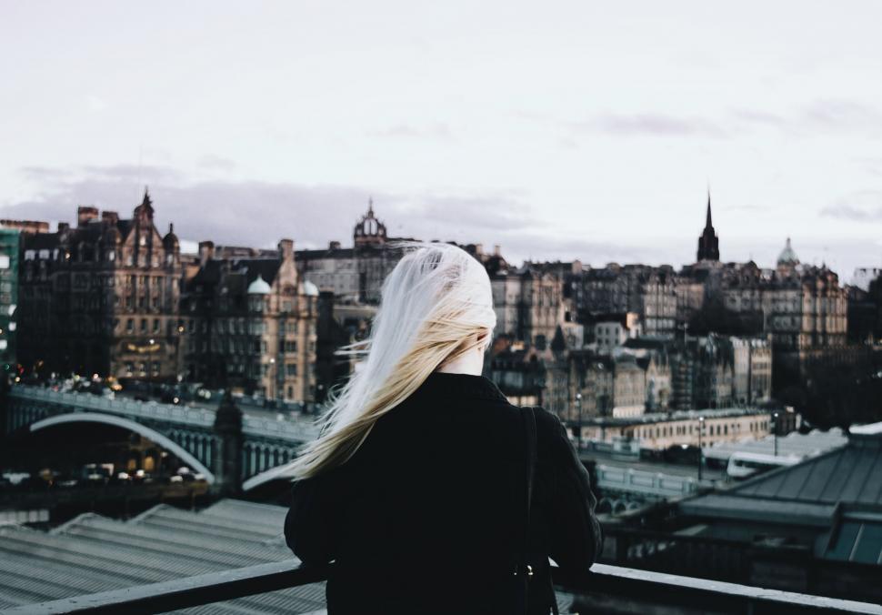 Free Image of Blonde woman overlooking city skyline at dusk 