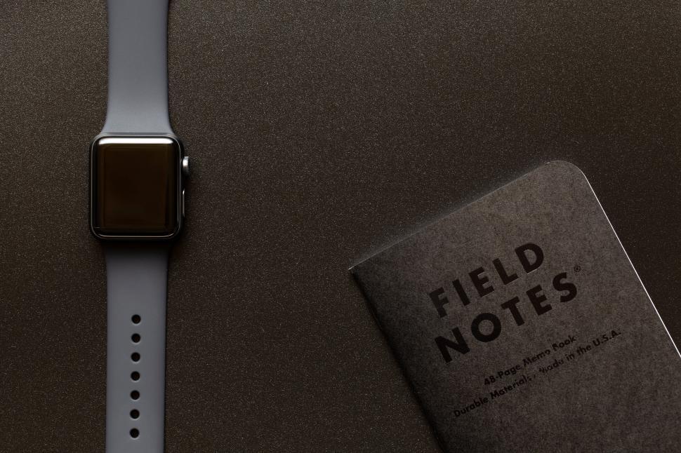 Free Image of Smartwatch beside a notebook titled  Field Notes 