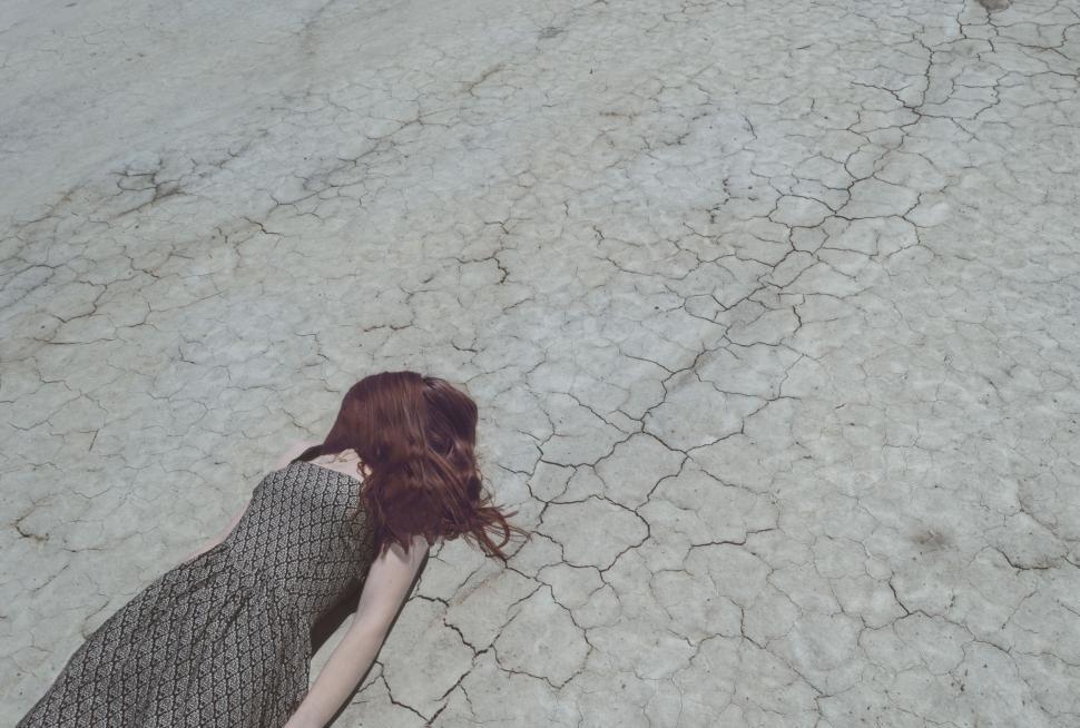 Free Image of Woman lying on cracked desert soil 