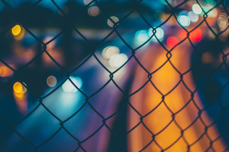 Free Image of Bokeh lights seen through chain-link fence 