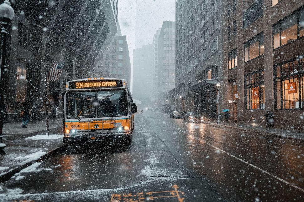 Free Image of Snowy city street with yellow bus in motion 