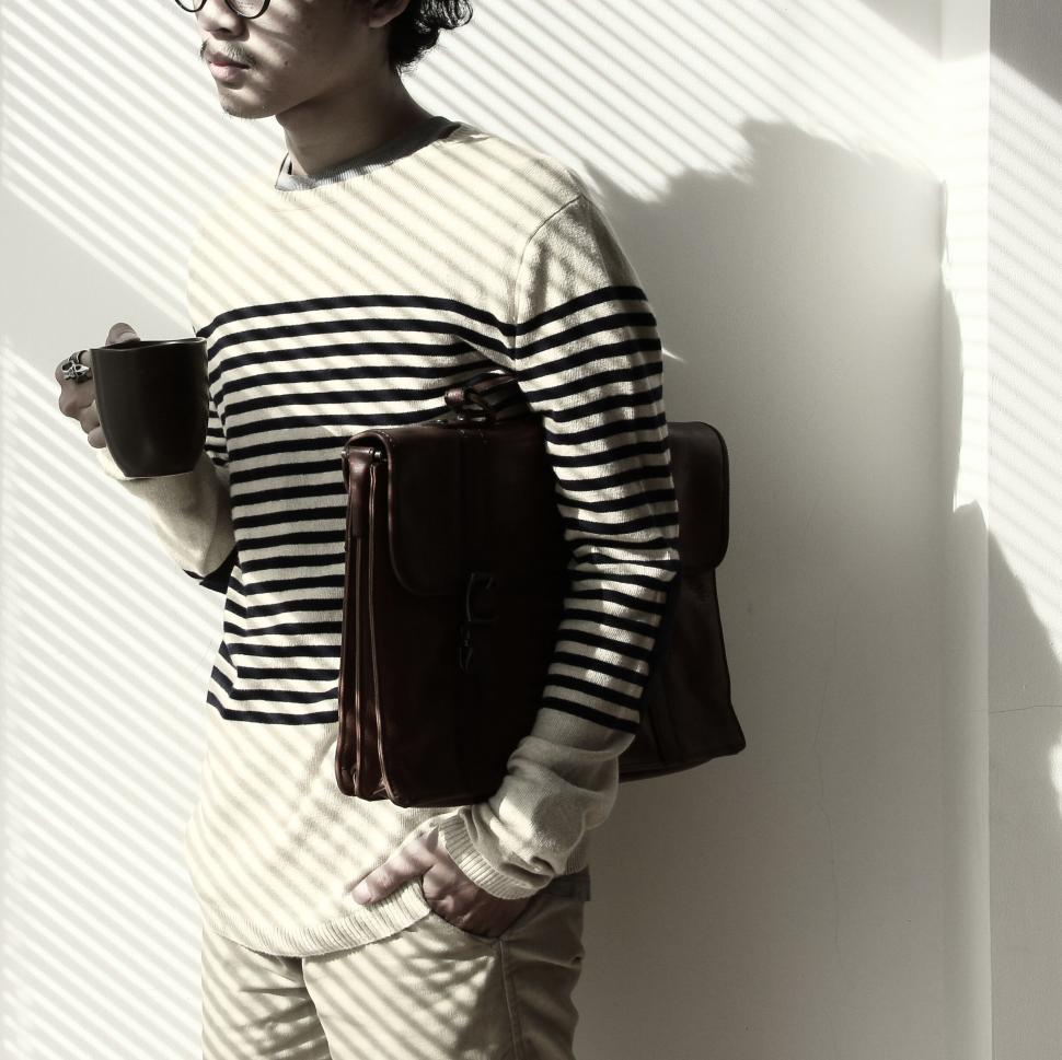 Free Image of Man with coffee and backpack in striped attire 