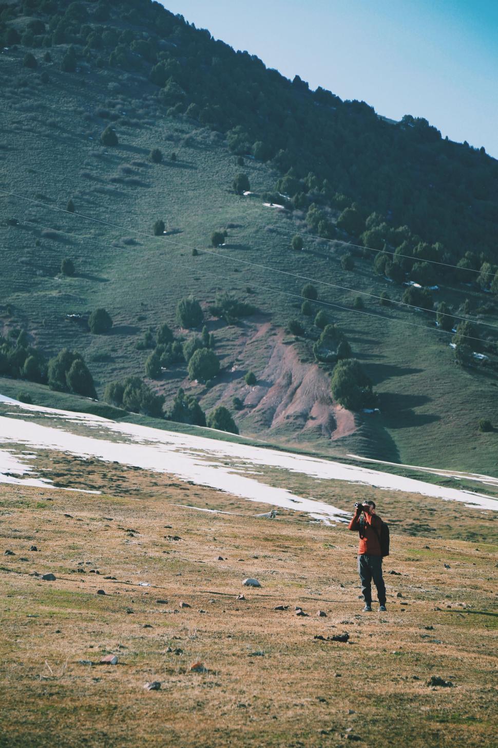 Free Image of Hiker in red on mountain with snow patches 