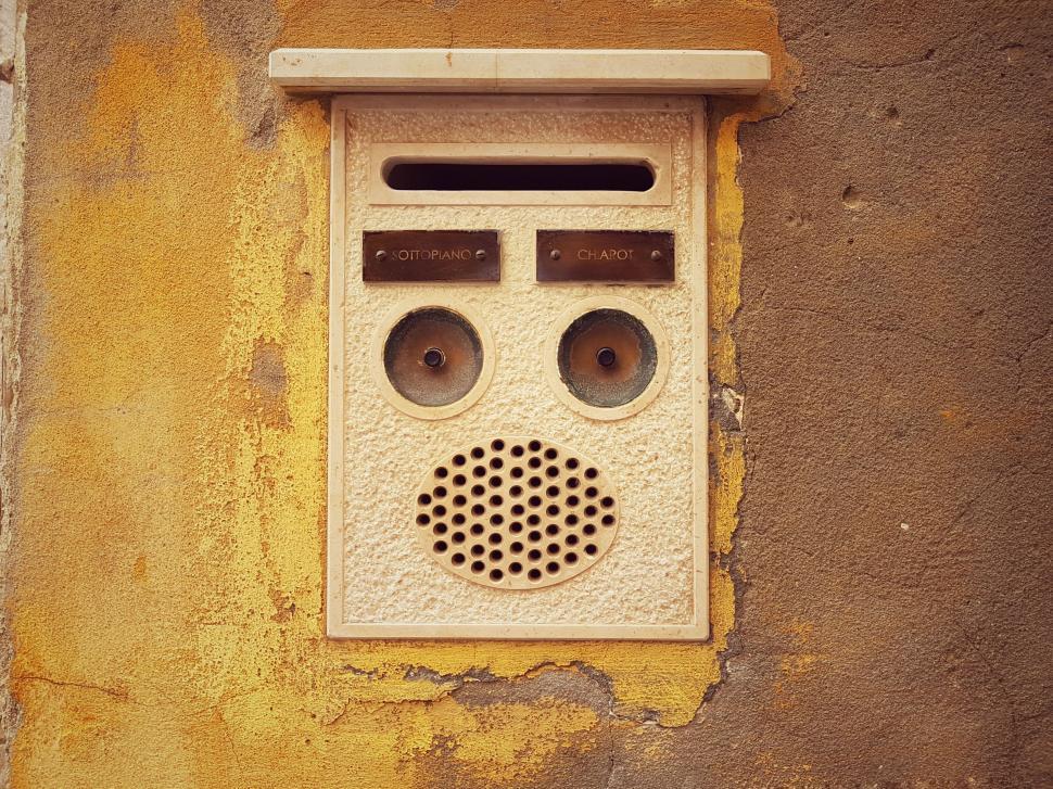 Free Image of Vintage intercom on a textured yellow wall 