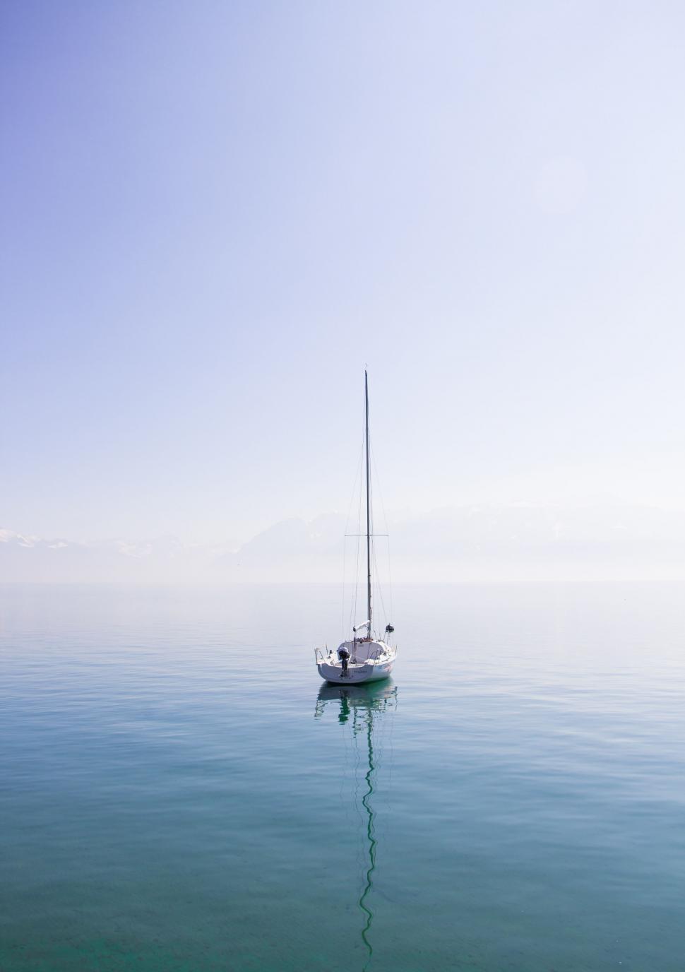 Free Image of Sailboat in serene water with mountains 