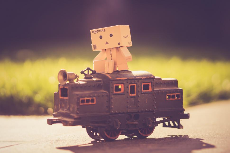 Free Image of Amazon box robot sits atop a miniature train 