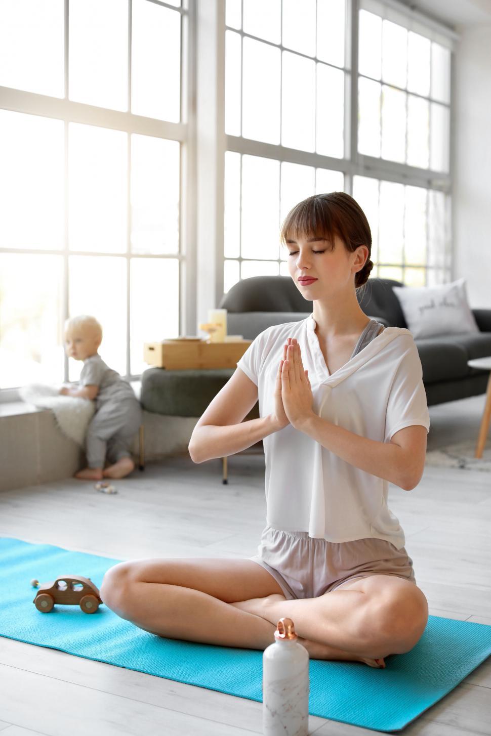 Free Image of Mother doing yoga with baby in background 