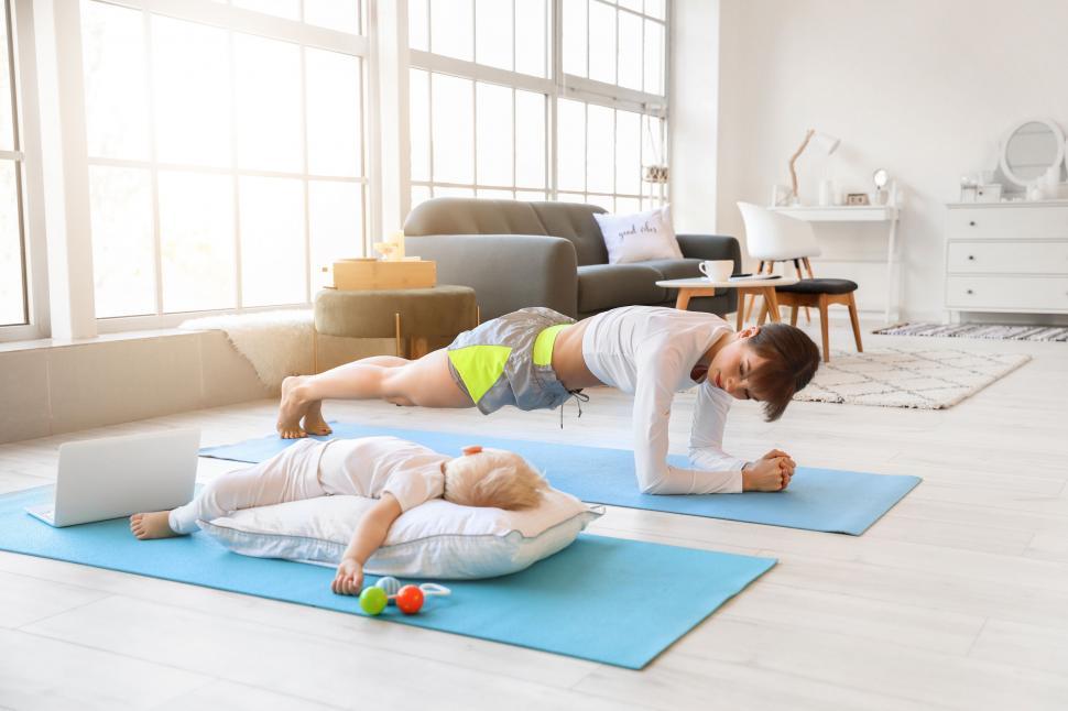 Free Image of Mother planking with a sleeping child during workout 