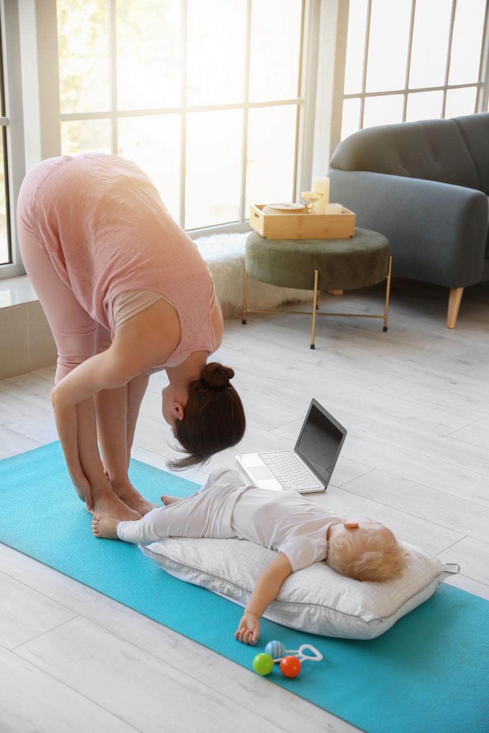 Free Image of Practicing yoga stretches near a sleeping child 