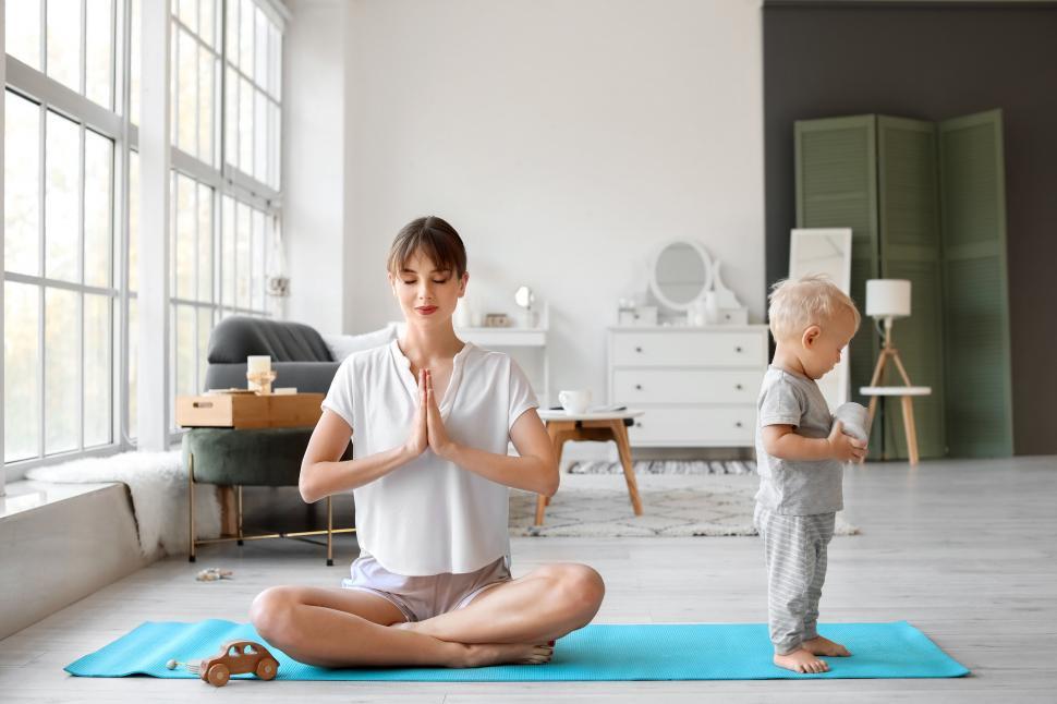 Free Image of Mother practices yoga while toddler explores 