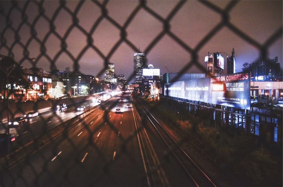 Free Image of City nightscape through a chain-link fence 