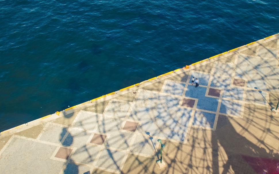 Free Image of Aerial shot of people walking on a sunny pier 