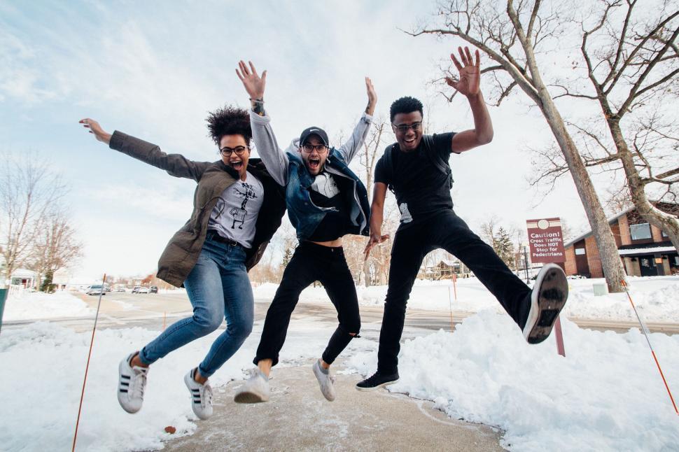 Free Image of Three friends jumping joyfully in the snow 