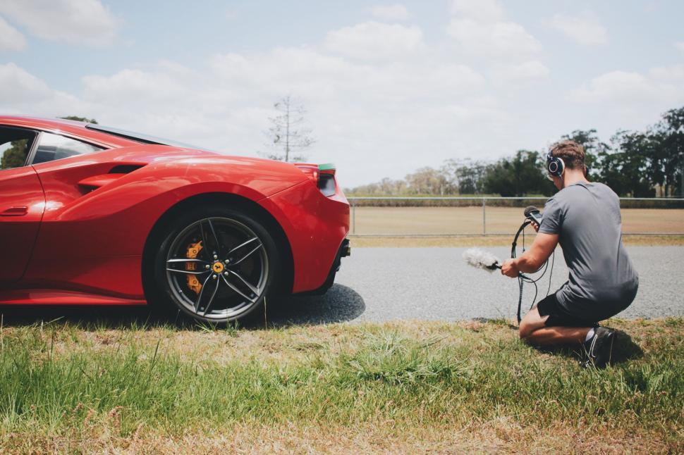 Free Image of Photographer capturing a red sports car on a racetrack 