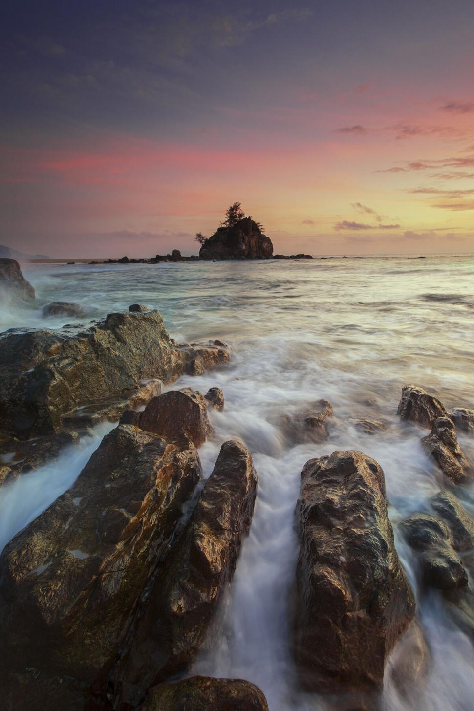 Free Image of Sunset seascape with rocky shoreline and island 