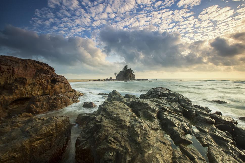 Free Image of Rocky shoreline and cloudy sky at sunrise 