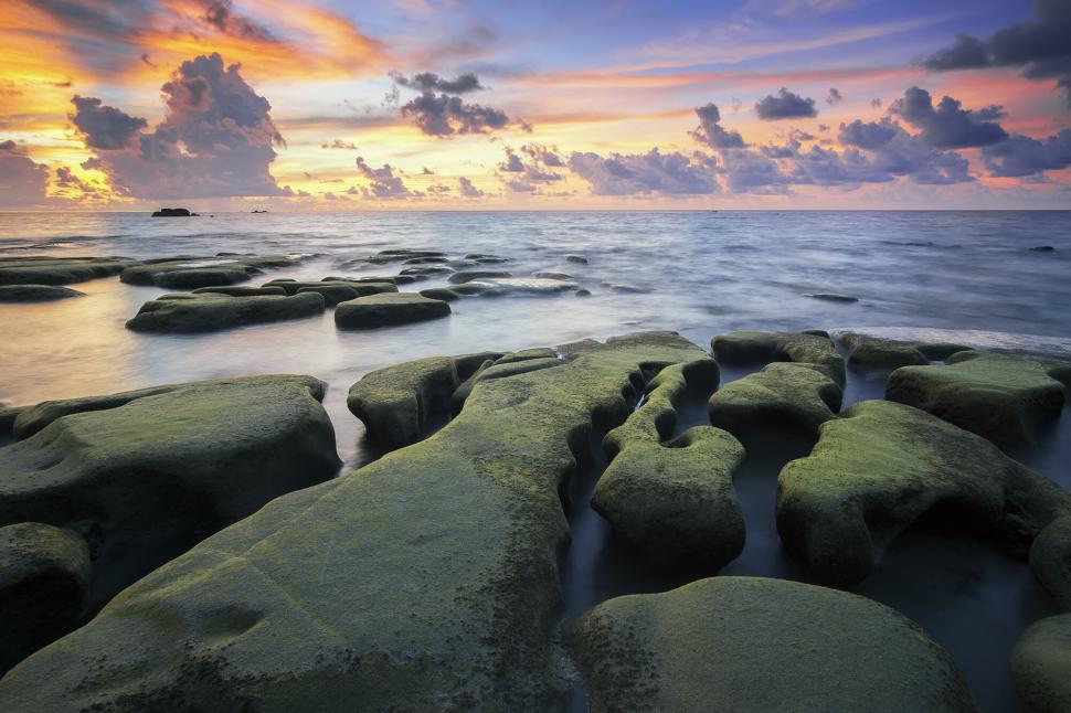 Free Image of Moss-covered rocks leading into sunset ocean 