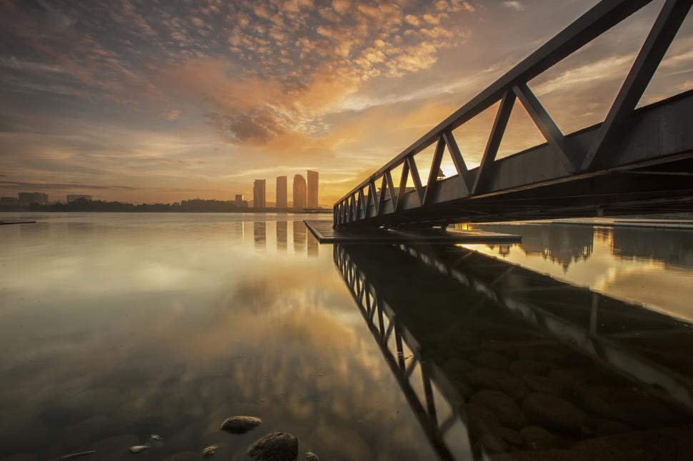 Free Image of Sunrise over calm lake with steel bridge 