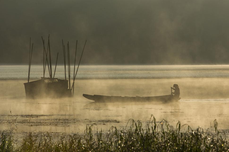 Free Image of Misty lake scene with fisherman and boat 