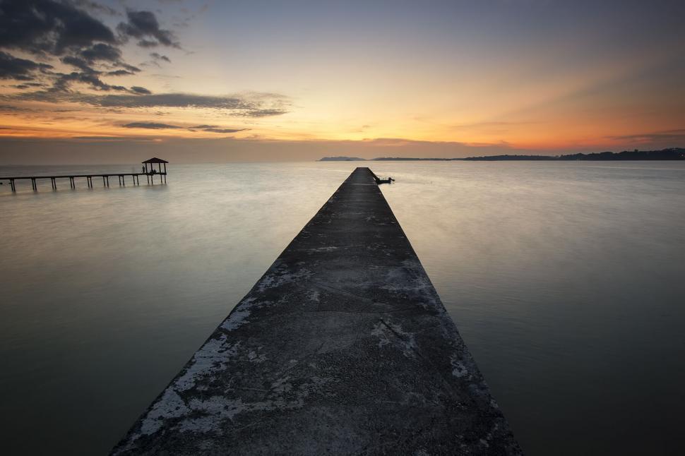 Free Image of Sunset casting warm hues over a pier 