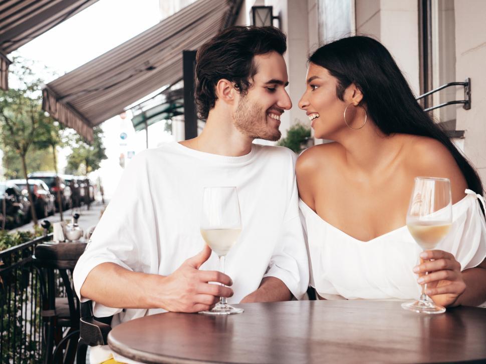 Free Image of A man and woman sitting at a table with wine glasses 