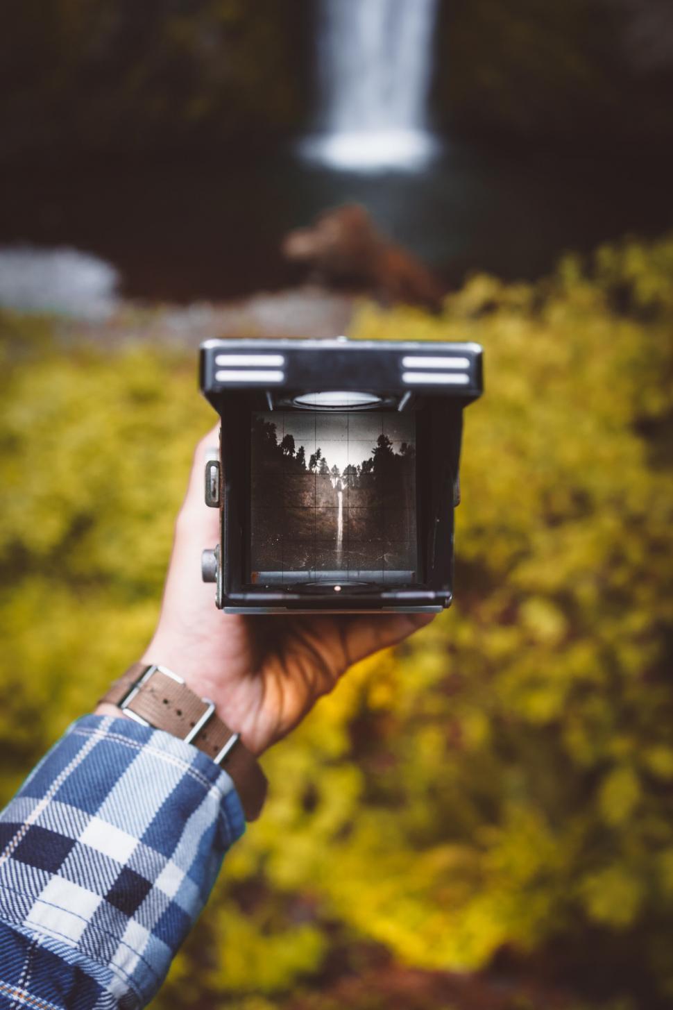 Free Image of Person holding camera with waterfall 