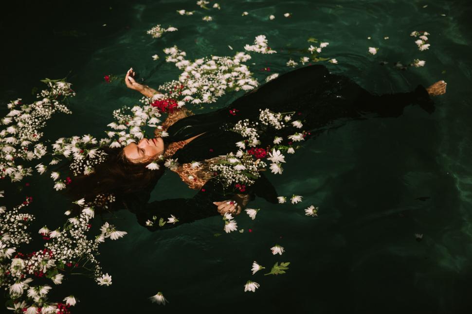 Free Image of Woman floating in water with flowers 