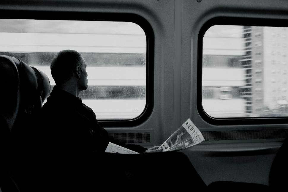 Free Image of Man reading in train window reflection 