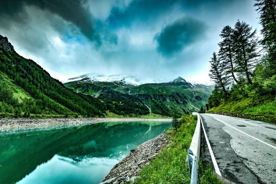 Free Image of Mountainous lakeside road with overcast skies 
