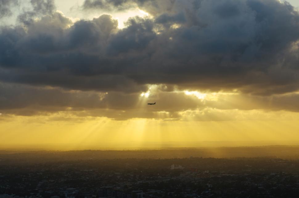 Free Image of Sunset with sunbeams through clouds over city 