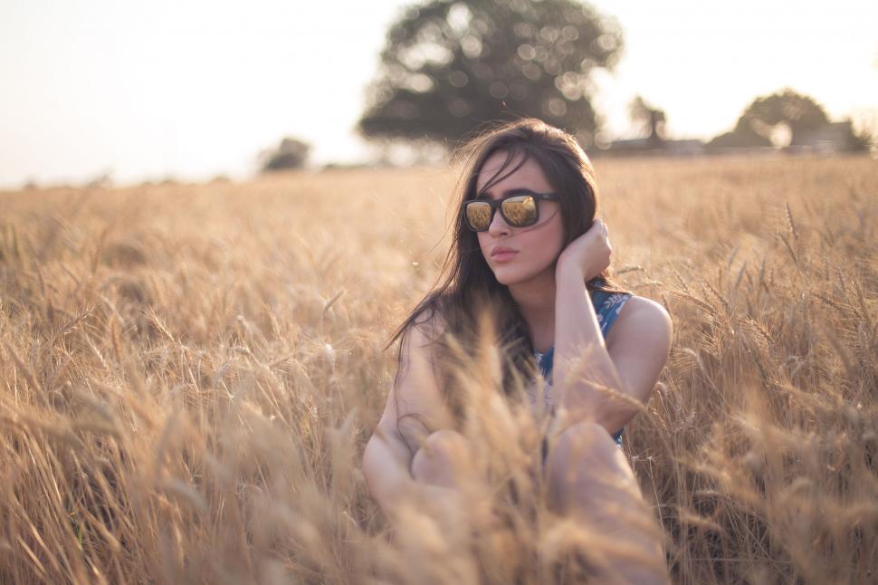 Free Image of Woman sitting in a golden wheat field 