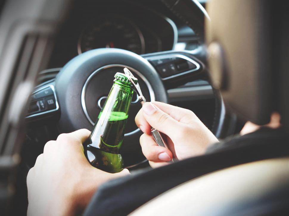 Free Image of Close-up of person opening bottle while driving 