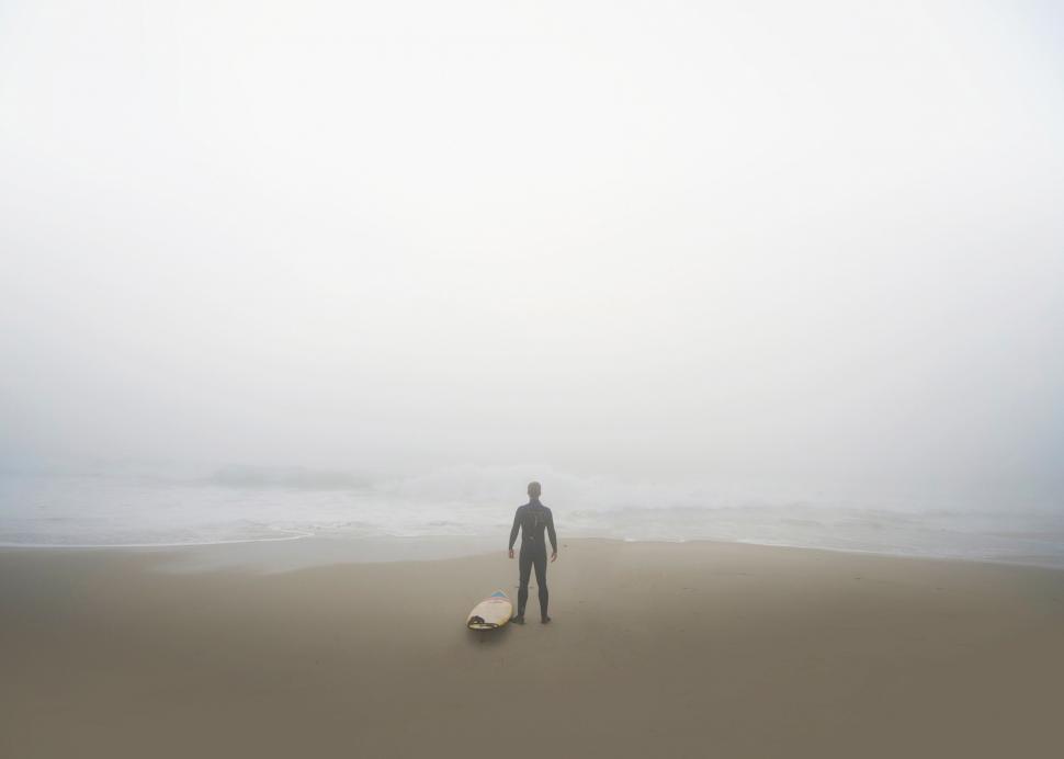 Free Image of Surfer gazing into foggy seascape 