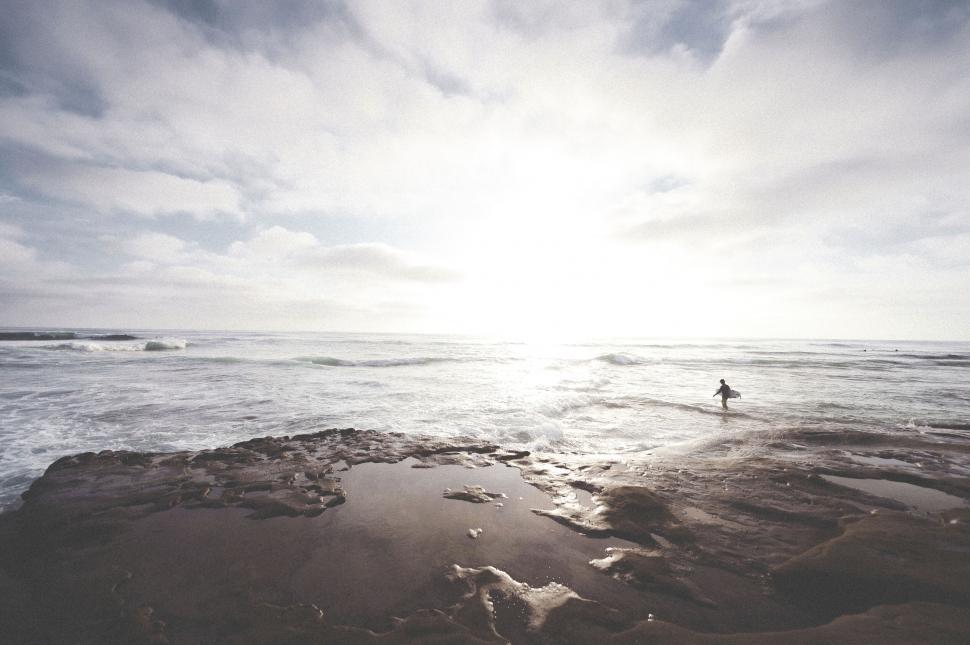 Free Image of Surfer entering sunlit ocean waves 