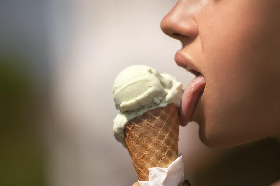 Free Image of Hand holding an ice cream cone with a blurred face 