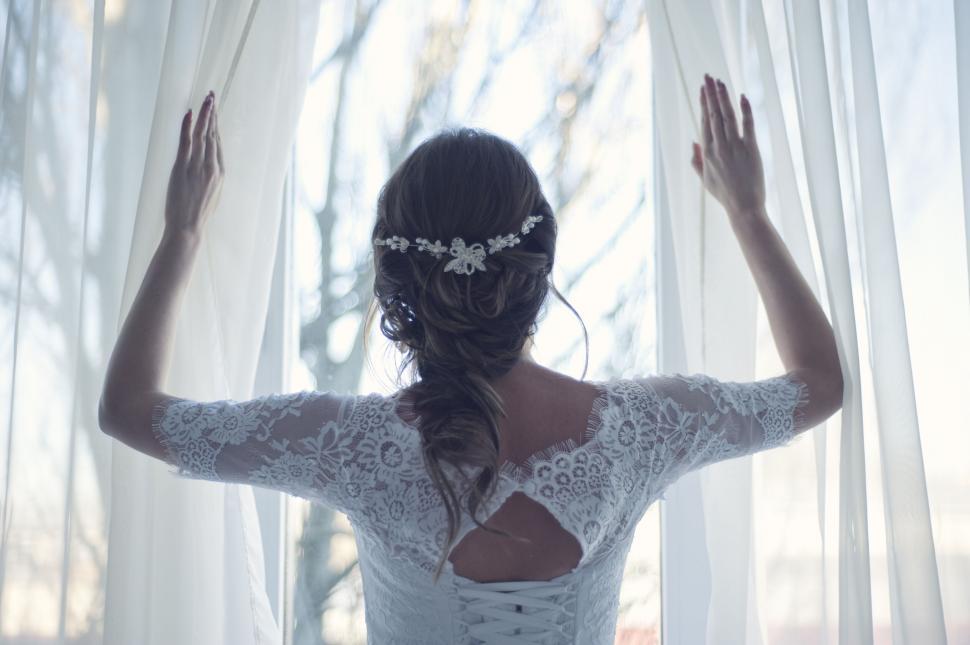 Free Image of Bride looking out the window in her gown 