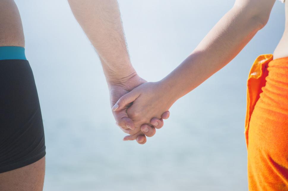 Free Image of Couple holding hands at the beach 