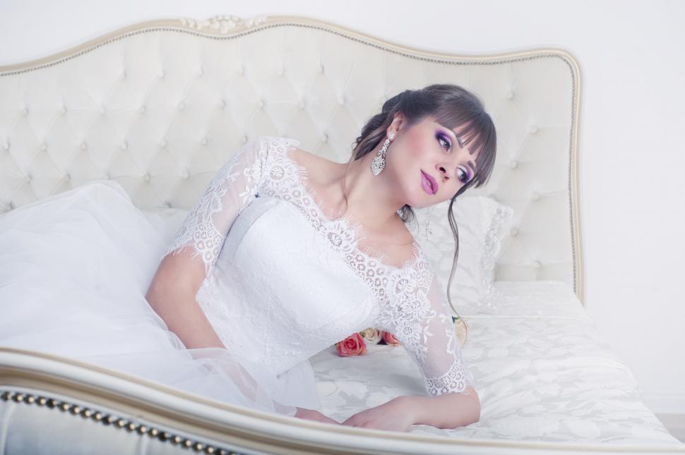 Free Image of Face-blurred bride lying on a bed in gown 