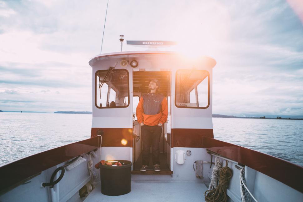 Free Image of Man standing on boat at sunset 
