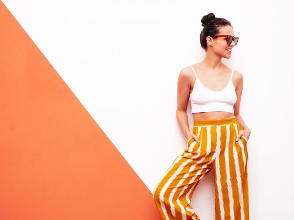 Free Image of A woman in a white tank top and orange striped pants 