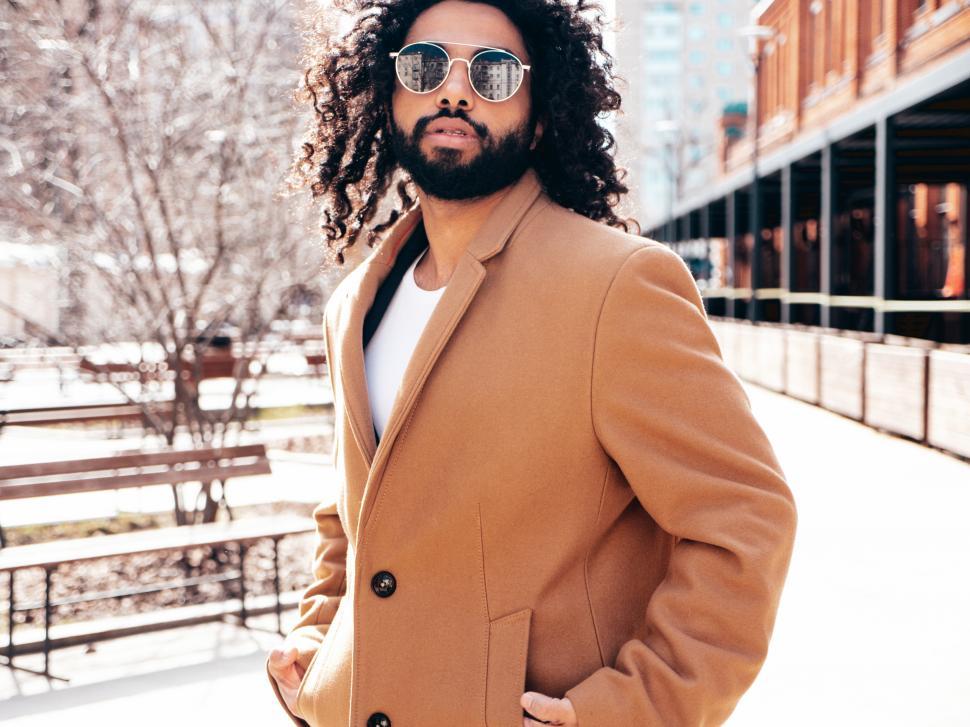 Free Image of A man with long curly hair wearing sunglasses and a brown coat 