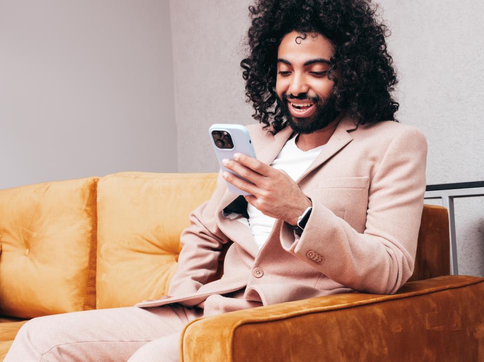 Free Image of A man sitting on a couch looking at a cellphone 
